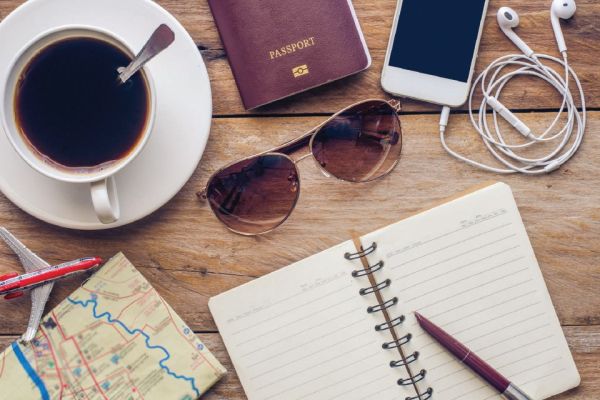 travel planning table with sunglasses, map, notepad and coffee cup