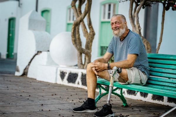 Senior man in shorts with above-knee amputation resting on bench